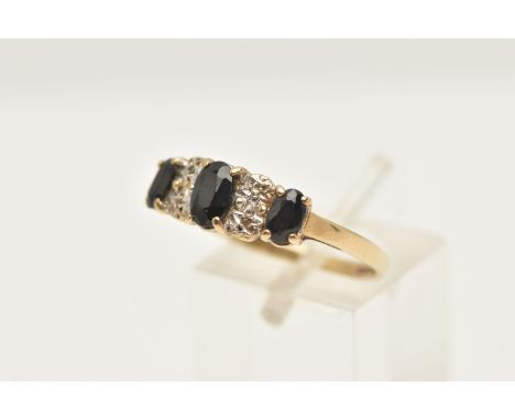 A 9CT GOLD SAPPHIRE AND DIAMOND RING, set with three oval cut deep blue sapphires each in a four claw setting, with single cu