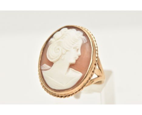 A 9CT GOLD CAMEO RING, of an oval form, set with an oval carved shell cameo depicting a lady in profile, collet set within a 