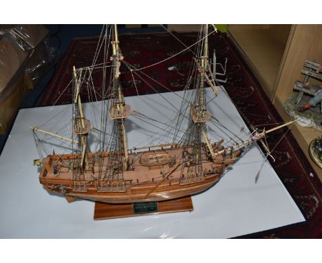 A WOODEN KIT BUILT MODEL SHIP OF HMS BOUNTY with rigging and miniature sailors, display present on the stand, height 63cm x w