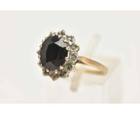 A 9CT GOLD SAPPHIRE CLUSTER RING, of an oval form, set with a central oval cut deep blue sapphire, claw set within a surround