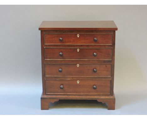 A miniature mahogany chest of four drawers, in the Georgian style, raised on bracket feet, with ivory escutcheons, 22cm wide