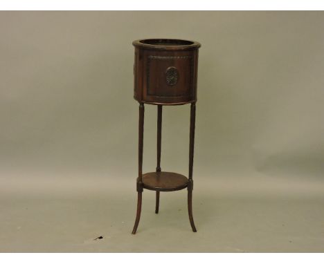 A mahogany jardinière stand, cylindrical form on three fluted supports, tiered shelf and splay feet, 95cm high, 33.7cm wide, 