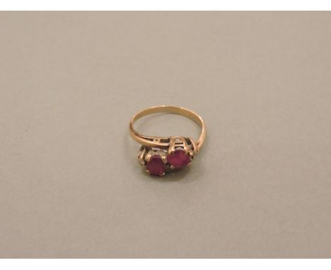 A gold two stone ruby crossover ring, flanked by two diamonds, stamped 375