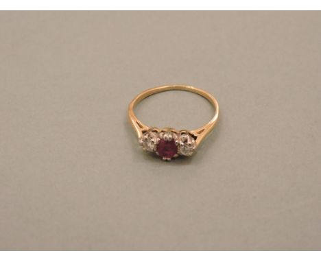 A gold ruby and diamond three stone ring, oval cut ruby flanked by two brilliant cut diamonds