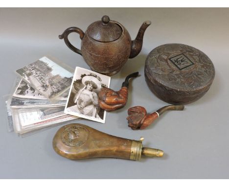 A collection of postcards, two wooden pipes including one of a gentleman's face, a gunpowder flask, a carved wooden box, and 