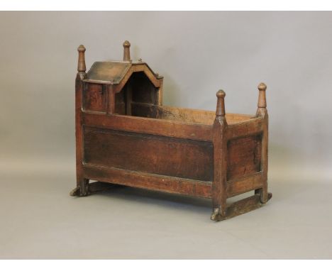 A late 17th century oak crib, of framed panel construction with an angled canopy and turned post, Provenance: from a prominen