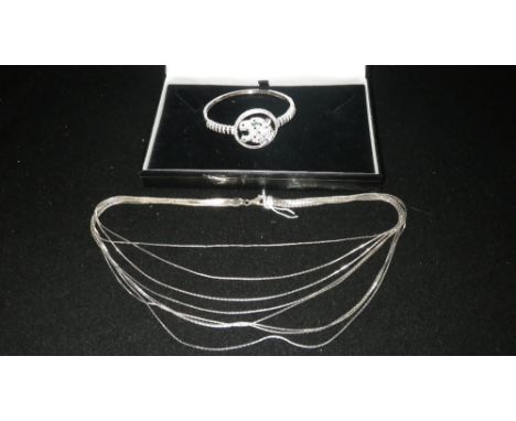A WHITE METAL BANGLE decorated with a tiger's head within an openwork frame and a silver multi-stranded necklace (2)