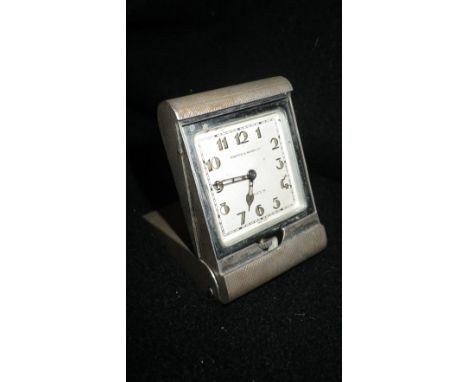 FORTNUM & MASON LTD: A FOLDING TRAVELLING CLOCK in an engine-turned silver case