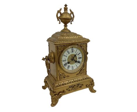 A 19th century gilt metal mantel clock, the white enamel dial set with Roman numerals and the top surmounted with urn decorat
