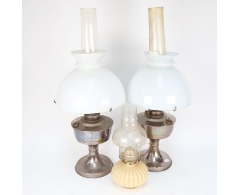 A pair of chrome oil lamps, with chimneys and milk glass shades, height 59cm, and a small oil lamp 