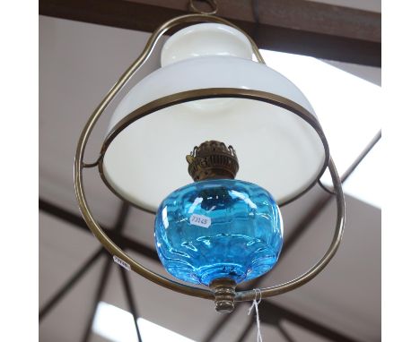 A hanging glass oil lamp with brass mounts, having a blue font and milk glass shade, diameter overall 33cm 