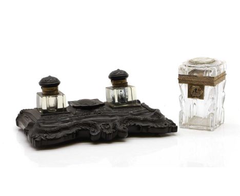 A Victorian carved ebony desk stand, centred with a hinged compartment, flanked with cut glass inkwells, with carved hinged c