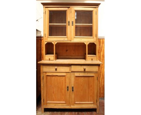 A 20th century stripped pine kitchen dresser with moulded cornice, a pair of glazed doors enclosing shelf above open storage 