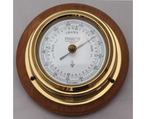 A Wempe bulkhead aneroid barometer in oak-mounted lacquered circular brass case, 17cm diameter