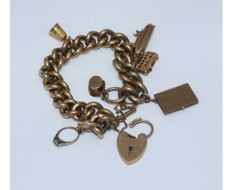 A heavy 9ct gold curb-link bracelet with heart-shaped lock-clasp and seven charms including top-hat, thimble, ring, key, pass