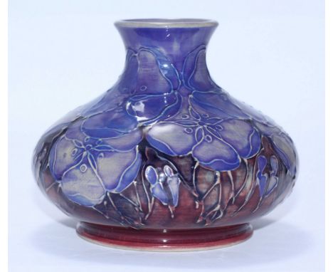 A Moorcroft pottery vase in a pastel blue floral pattern to a red ground, of compressed globular form, limited edition 5/100,