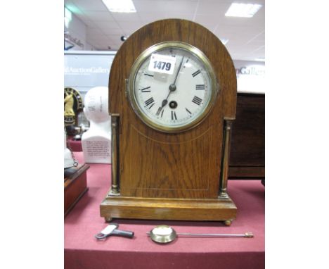 An Early XX Century Oak Cased Mantel Clock, arched top; boxwood stringing flanked by brass columns, white enamel dial, Roman 