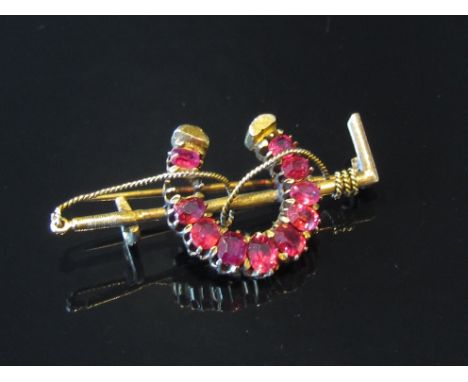 A ruby set horseshoe and riding whip brooch