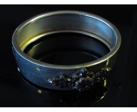 A stiff hinge bangle set with garnets, marks indistinct 