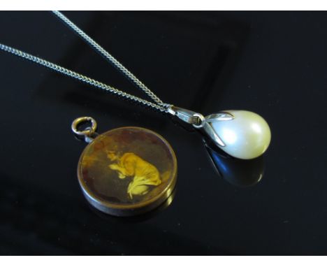 A single faux pearl drop necklace and a circular pendant depicting praying girl