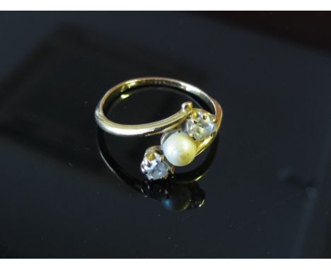 A cross over split pearl flanked by two diamonds, marks rubbed, size P, 2.6g