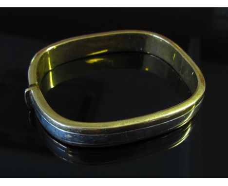 A two tone gold cushion shaped bangle, 10mm wide, stamped Italy 750, 28g