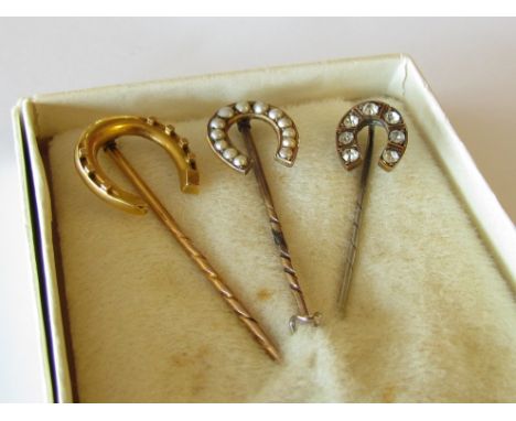 Three horseshoe shaped stick pins including two gold examples