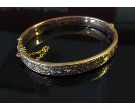 A wax filled 9ct gold stiff hinge bangle chased with ivy leaves, 15g