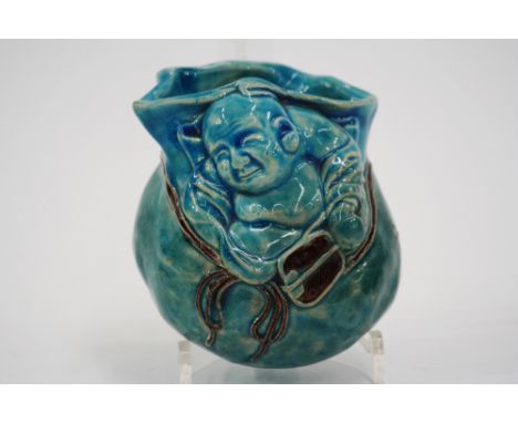 A Chinese turquoise pottery wall bracket, in the form of a seated Joss man with fan, 12cm
