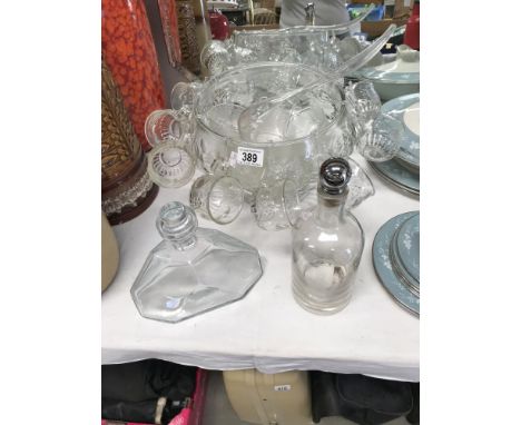 A glass punch bowl with 11 cups, 6 other punch cups, plastic ladle and hooks and 2 glass decanters