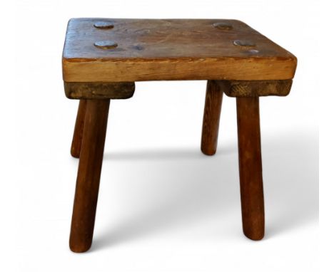 A rustic pine milking stool, rectangular top, 26cm high, 25cm wide, early 20th century