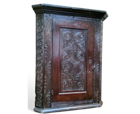 An early 19th century corner cupboard profusely carved throughout, 90cm x 80cm x 43cm