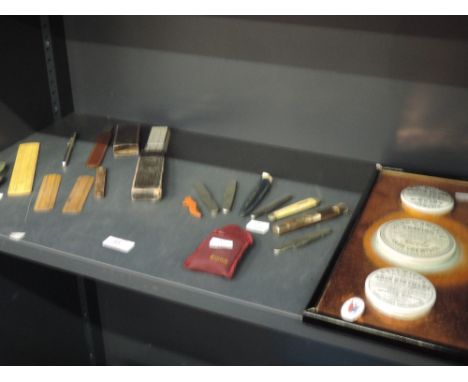 A copper mounted display of pot lids, a selection of pen knives, a Ronson lighter and a selection of rules
