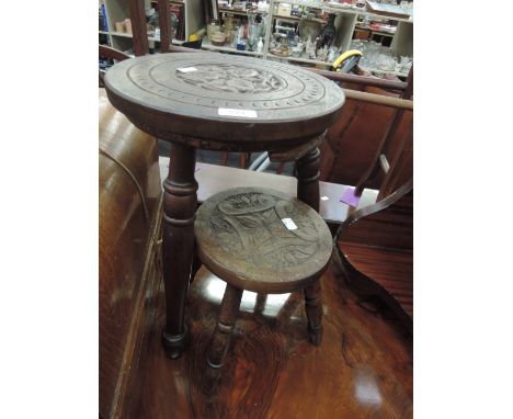 An oak stool having circular carved foliate top on three legs and a smaller similar 