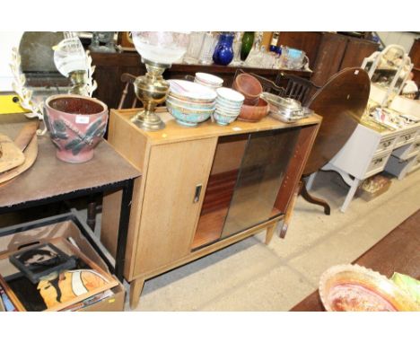 A teak bookcase with sliding glass doors and glass shelf