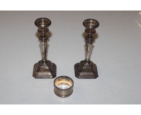 A pair of silver candle sticks with filled  bases and a silver napkin ring