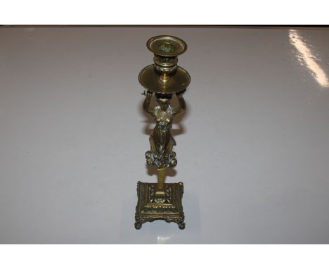 An ornate brass candlestick with female decoration 