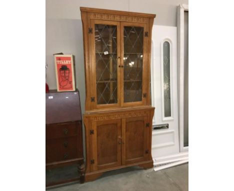 A light oak corner cupboard with leaded glass doors
