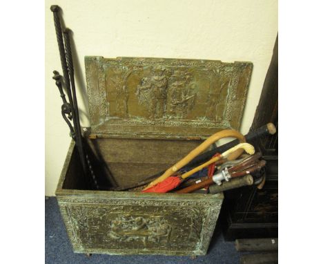 Brass repousse log box containing assorted shooting sticks, umbrellas, fire tools, pokers, hockey stick, faux ivory parasol e