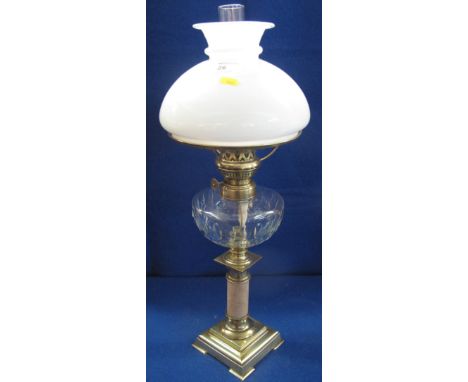 20th Century brass square section oil lamp with clear glass reservoir, funnel and cream shade. The button marked S.H or H.S. 