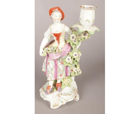 An 18th century Derby porcelain figural candlestick modelled as a lady collecting flowers. 25cm.  Some missing foliage and ti