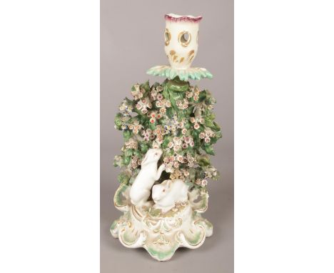 An 18th century Derby porcelain candlestick, with white rabbits, bocage and floral thumbpiece to handle. 23cm.  Firing cracks