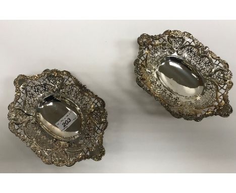 A pair of Victorian pierced silver sweetmeat dishes with foliate and floral scrollwork decoration, raised on four similarly d