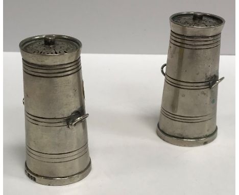 A pair of late Victorian novelty peppers as milk churns with pierced grilles over slightly tapering bodies with side handles,