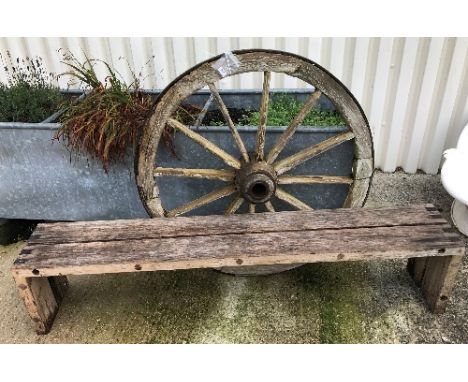 A modern wooden slatted garden bench, 190 cm wide, together with a wrought iron bound wagon wheel, 115 cm diameter