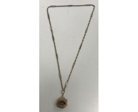 A 9 carat gold mounted pendant set with swivel caboshon cut tiger's eye and jade beads on an associated chainlink necklace 
