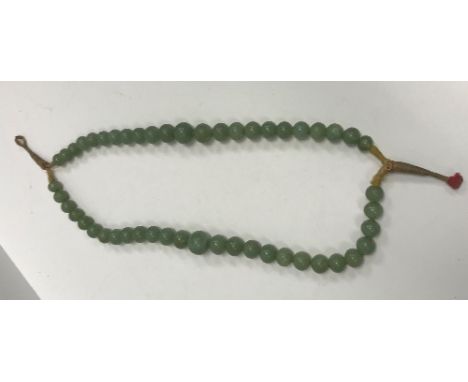 A 19th Century Chinese jade two strand bead necklace, knotted and with thread fastening, largest bead 1.8cm diameter smallest