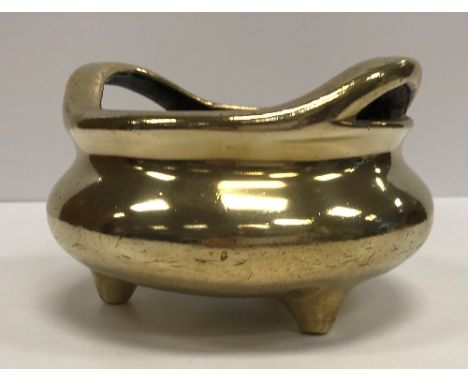 A Chinese bronze censer with openwork handles, raised on three feet, bearing sixteen character mark to base (probably faux Qi