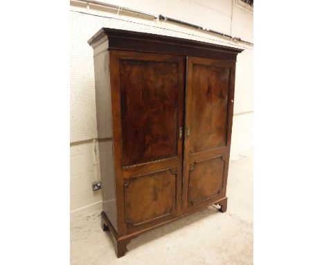 A late George III mahogany two door cupboard, the cornice with moulded decoration over two twin-panelled doors enclosing hang