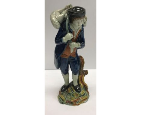 An early 19th Century Staffordshire pearlware figure of a shepherd with lamb across his shoulders by a tree stump, hollow bas